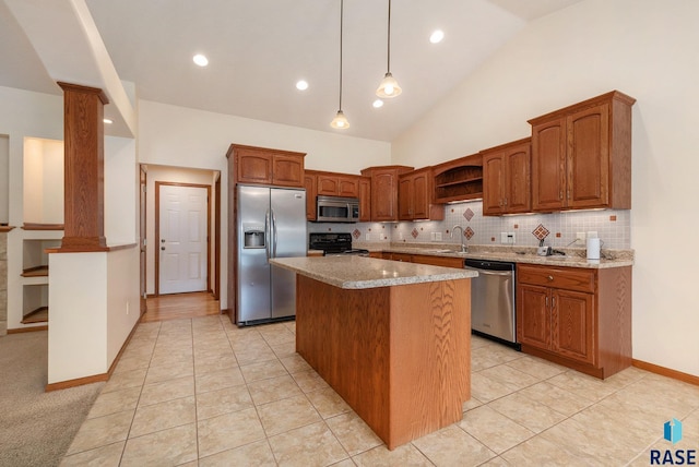 kitchen featuring appliances with stainless steel finishes, decorative columns, light stone counters, a kitchen island, and hanging light fixtures