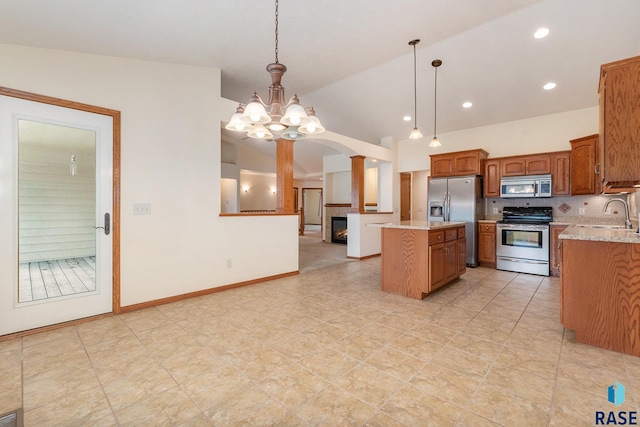 kitchen with backsplash, decorative light fixtures, lofted ceiling, a kitchen island, and appliances with stainless steel finishes