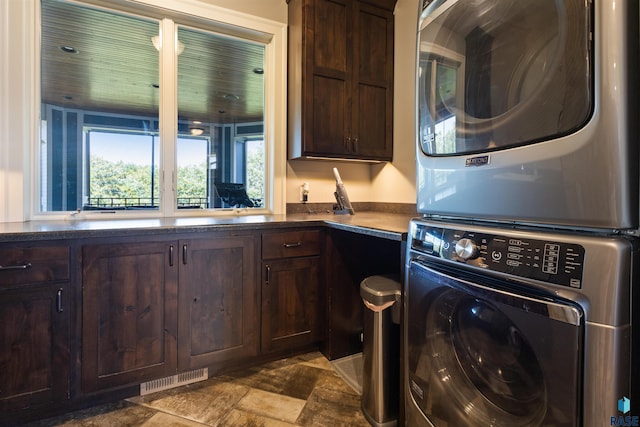 clothes washing area with cabinets and stacked washer / dryer