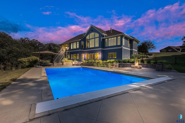 pool at dusk featuring a fire pit and a patio area