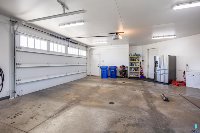 garage with stainless steel fridge with ice dispenser and a garage door opener