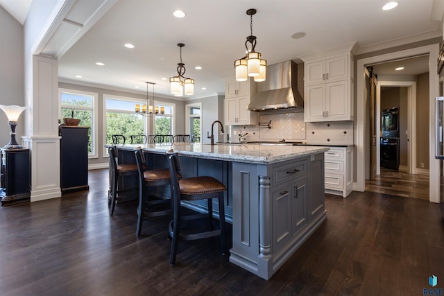 kitchen with white cabinets, dark hardwood / wood-style floors, a spacious island, and wall chimney range hood
