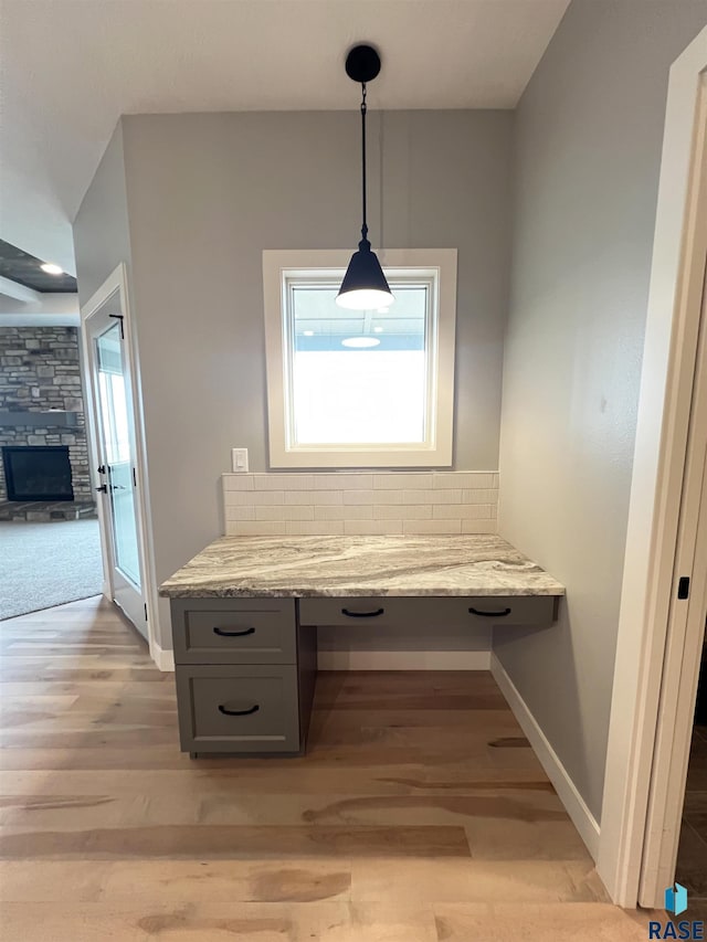 interior space with a stone fireplace, built in desk, and light hardwood / wood-style flooring