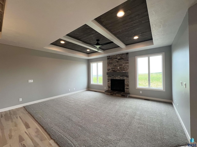 unfurnished living room featuring light colored carpet, a fireplace, and a tray ceiling