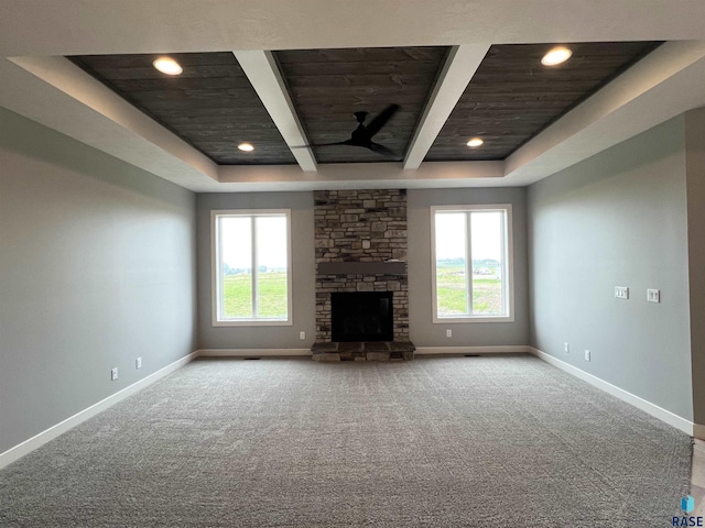 unfurnished living room with light colored carpet, a healthy amount of sunlight, and a stone fireplace