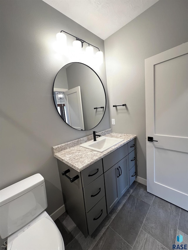 bathroom featuring vanity, a textured ceiling, and toilet