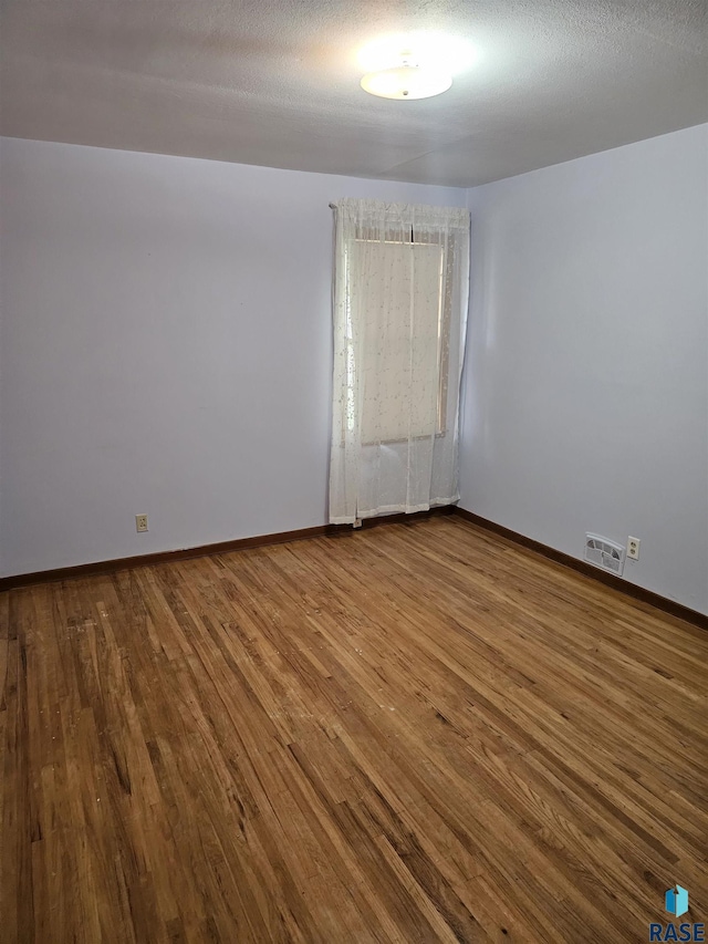 unfurnished room with hardwood / wood-style floors and a textured ceiling