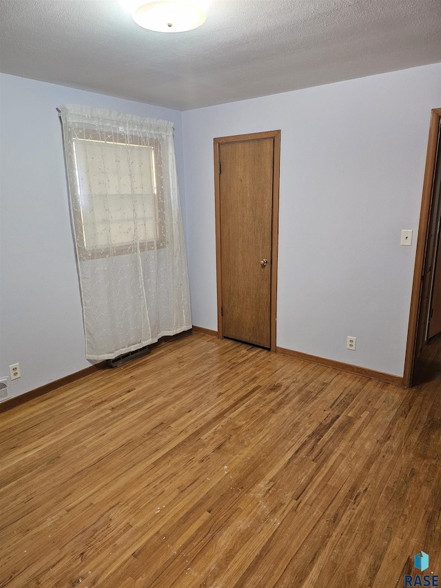 empty room featuring a textured ceiling and light wood-type flooring