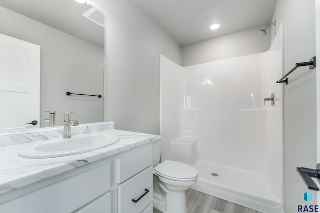 bathroom with vanity, wood-type flooring, toilet, and walk in shower