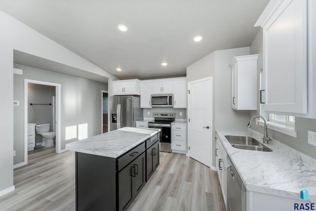 kitchen featuring white cabinetry, appliances with stainless steel finishes, vaulted ceiling, and a kitchen island