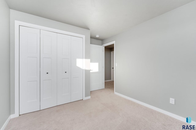 unfurnished bedroom with light colored carpet and a closet