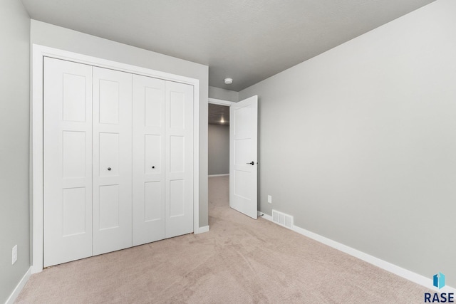 unfurnished bedroom with light colored carpet and a closet