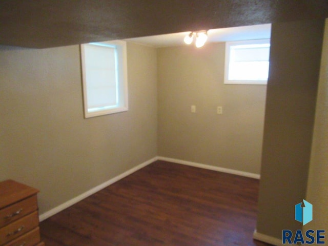 basement featuring dark wood finished floors and baseboards