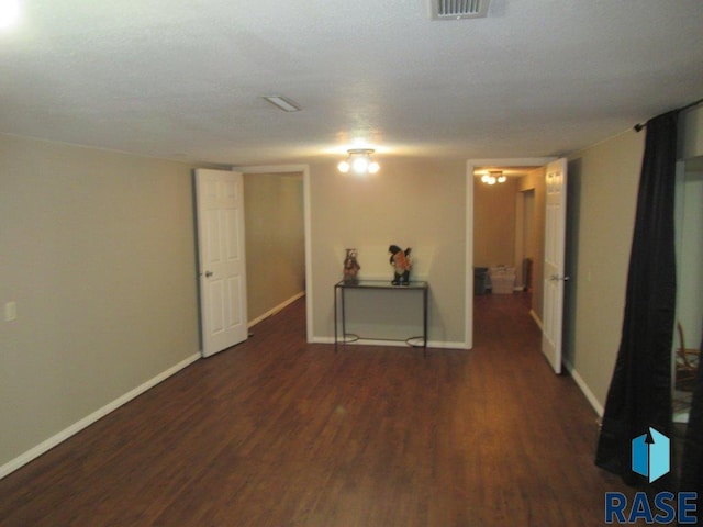 empty room with visible vents, baseboards, and dark wood-style flooring