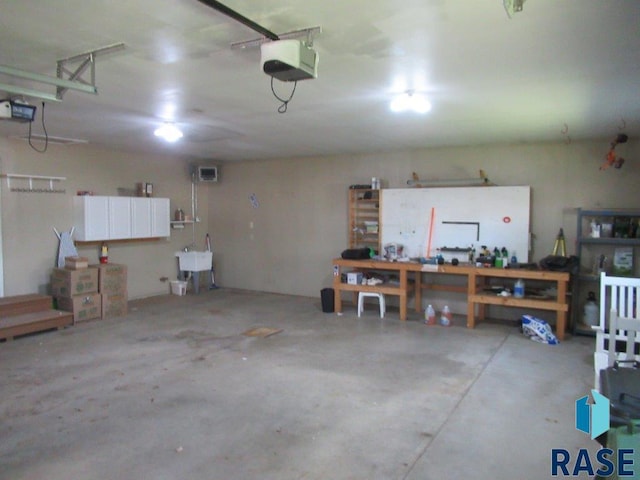 garage featuring a garage door opener, a sink, and a workshop area