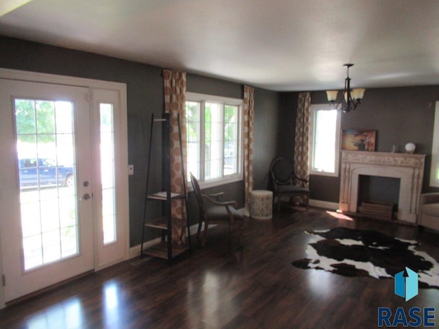 living room featuring a chandelier, dark wood-type flooring, a fireplace, and baseboards