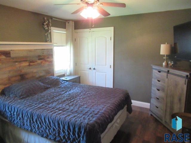 bedroom featuring a closet, dark wood finished floors, a ceiling fan, and baseboards