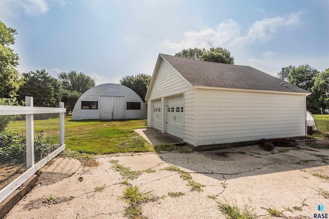 view of side of home featuring a garage, an outbuilding, and a yard