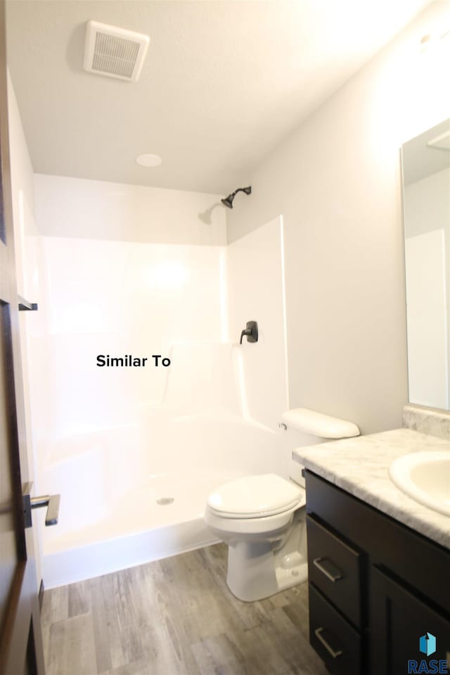 bathroom featuring vanity, a shower, hardwood / wood-style floors, and toilet