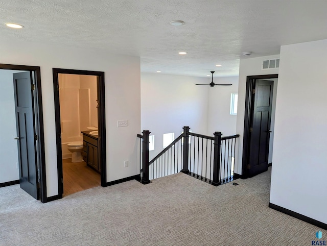 carpeted spare room with ceiling fan and a textured ceiling