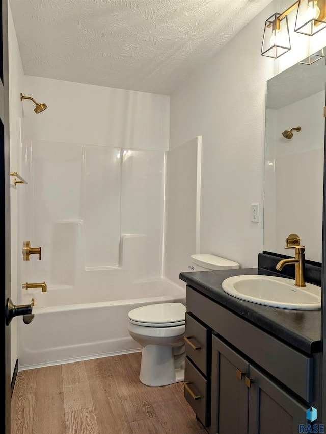 full bathroom with wood-type flooring, bathtub / shower combination, a textured ceiling, vanity, and toilet