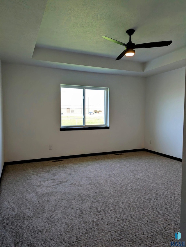 unfurnished room with carpet, a tray ceiling, and ceiling fan