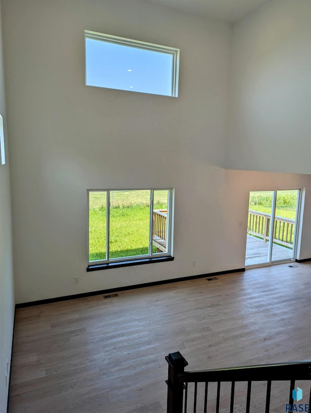 unfurnished living room featuring a towering ceiling and light wood-type flooring