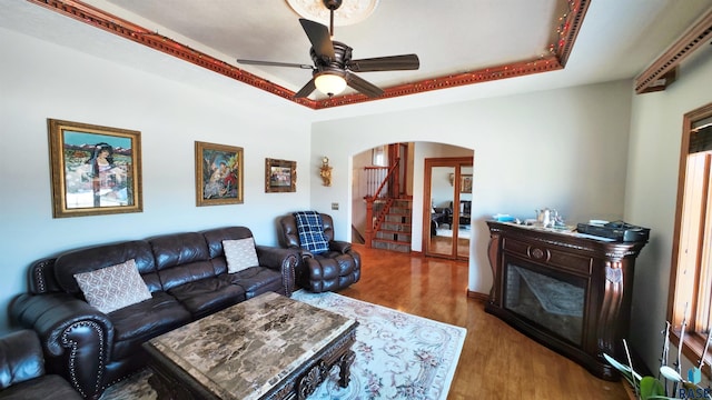 living room with ceiling fan, a raised ceiling, and hardwood / wood-style floors