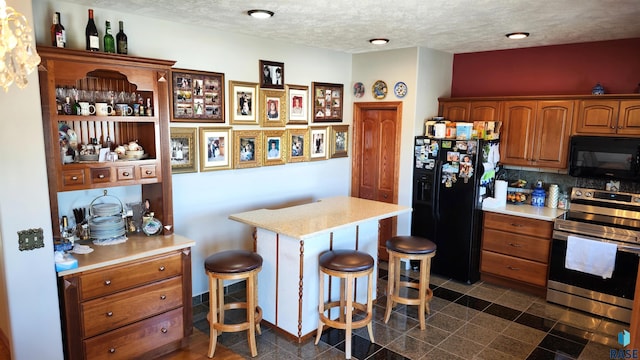 kitchen with a breakfast bar, tasteful backsplash, a center island, a textured ceiling, and black appliances