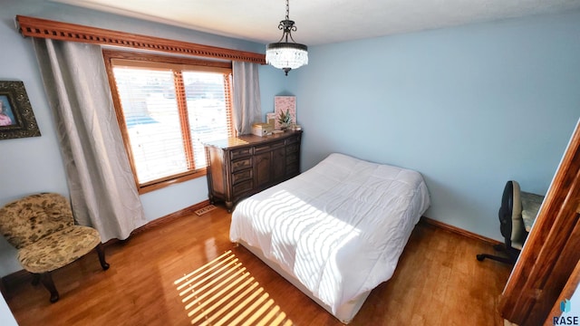 bedroom featuring an inviting chandelier and hardwood / wood-style floors