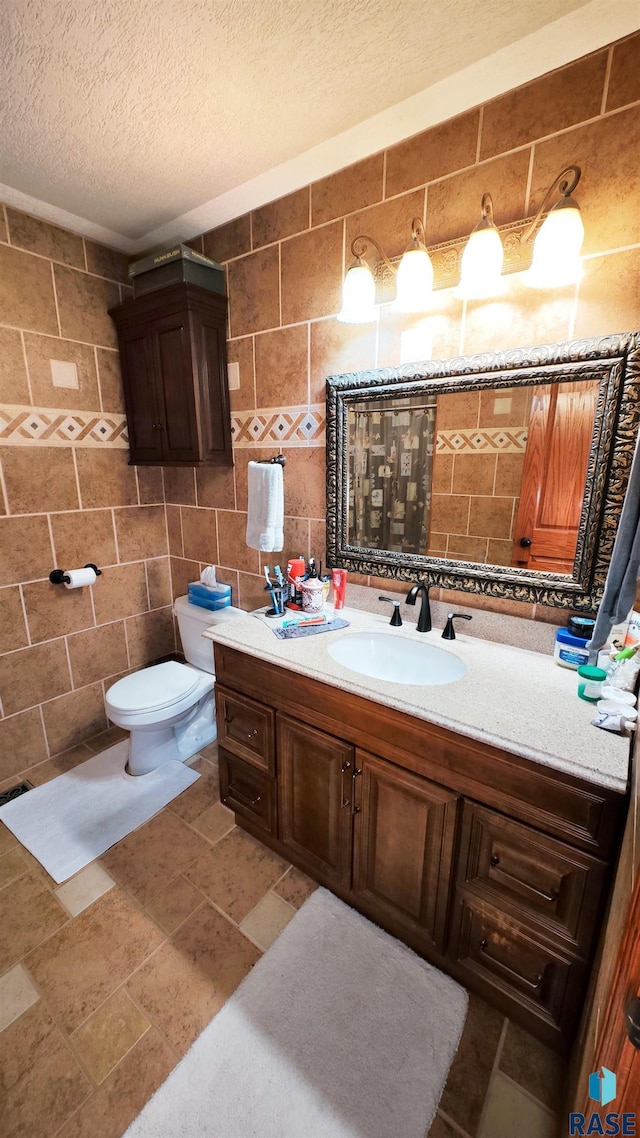 bathroom with tile walls, vanity, a textured ceiling, decorative backsplash, and toilet