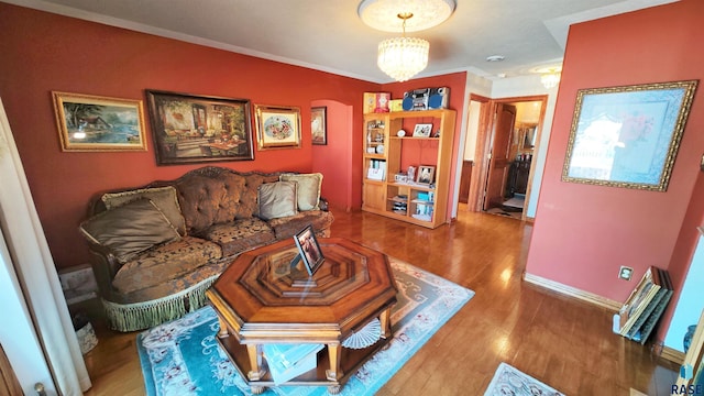 living room with an inviting chandelier, hardwood / wood-style flooring, and ornamental molding