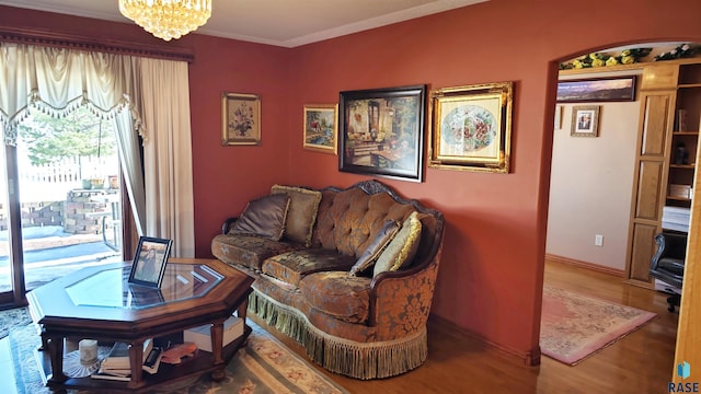 living room with ornamental molding, hardwood / wood-style floors, and a notable chandelier