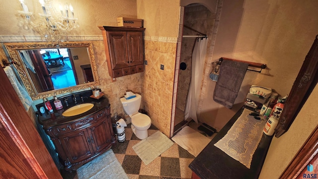 bathroom with tile walls, vanity, walk in shower, toilet, and an inviting chandelier