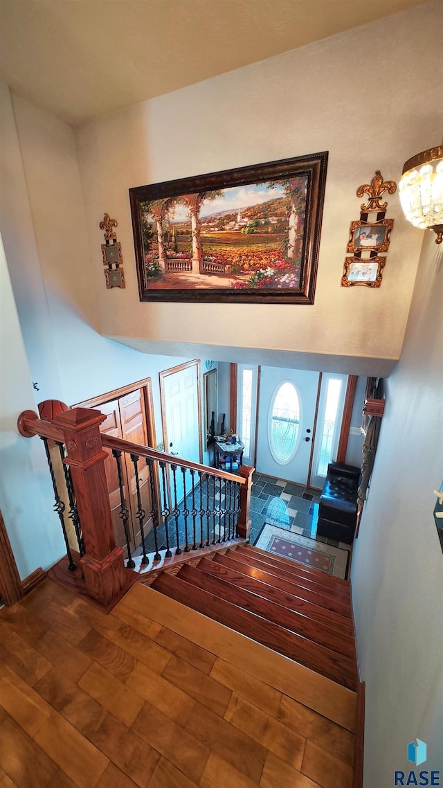 staircase with wood-type flooring and an inviting chandelier