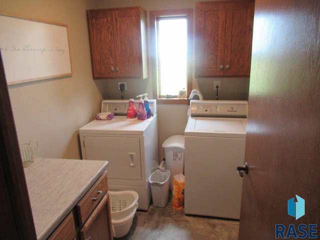 laundry area featuring light tile patterned floors, washing machine and clothes dryer, a healthy amount of sunlight, and cabinets