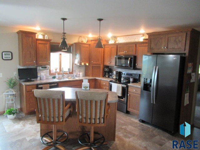 kitchen featuring decorative light fixtures, sink, a center island, appliances with stainless steel finishes, and light tile patterned floors