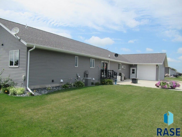 back of property with cooling unit, a garage, and a lawn