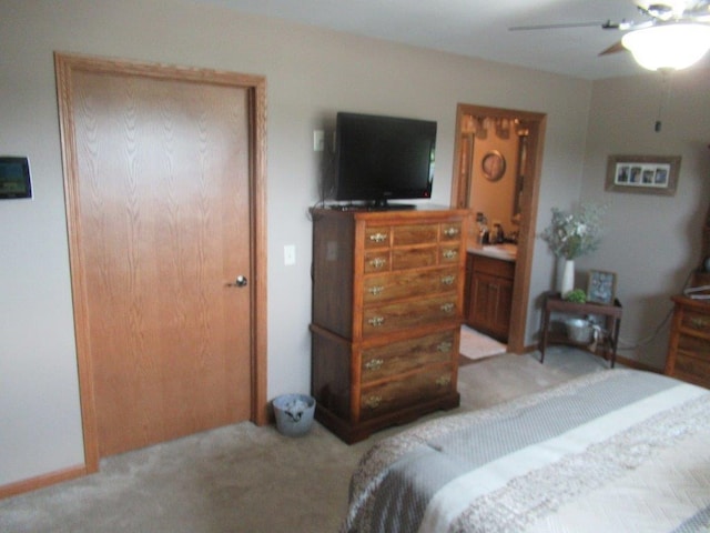 bedroom featuring light carpet, ensuite bathroom, and ceiling fan