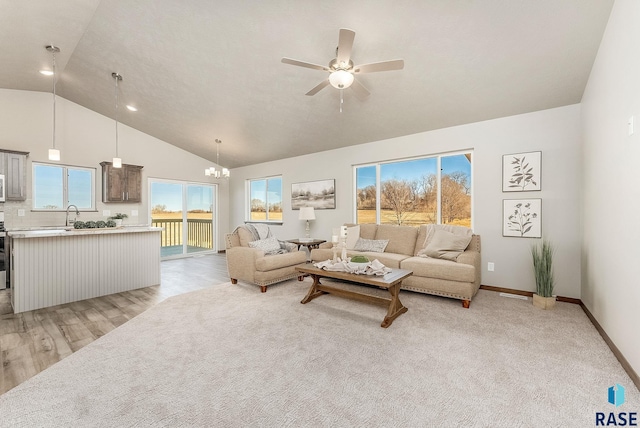 living room featuring ceiling fan with notable chandelier, light hardwood / wood-style floors, and high vaulted ceiling