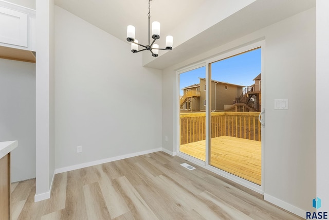 unfurnished dining area with an inviting chandelier and light wood-type flooring