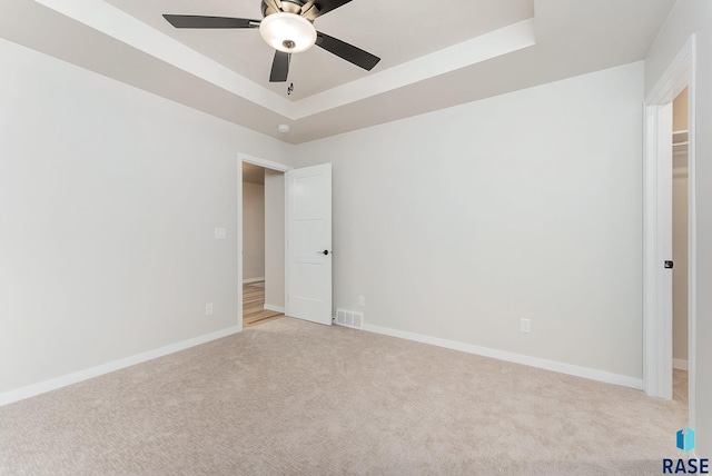 carpeted empty room featuring ceiling fan and a tray ceiling