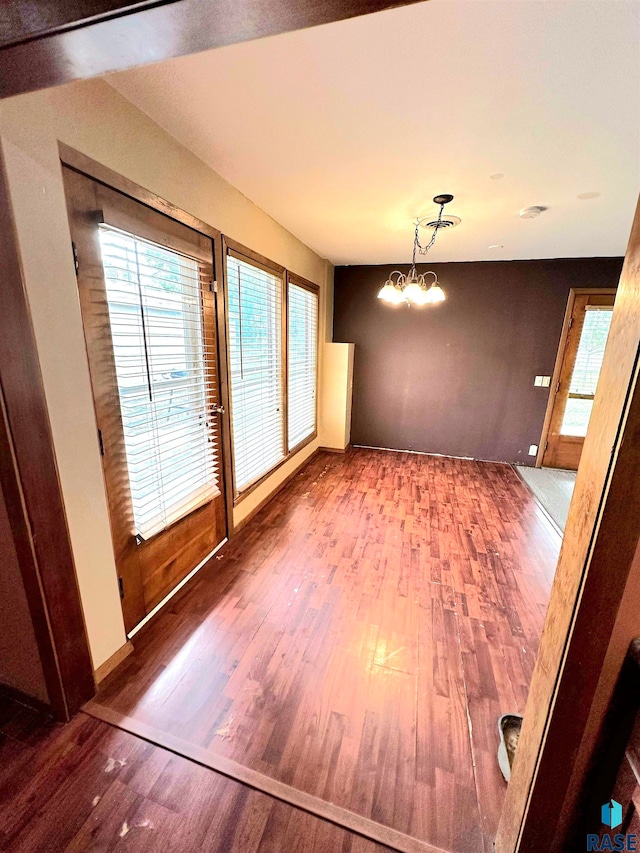 empty room with hardwood / wood-style floors and an inviting chandelier