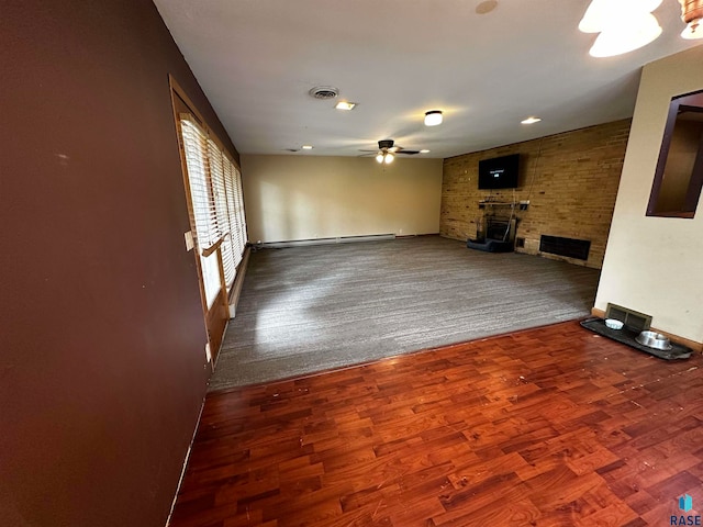 unfurnished living room with carpet floors, ceiling fan, a large fireplace, and a baseboard heating unit