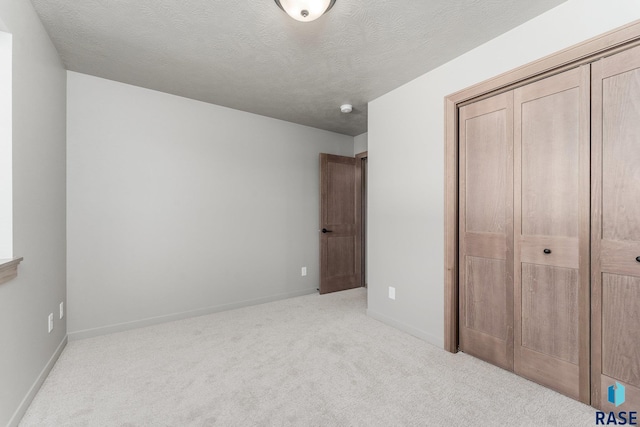 unfurnished bedroom with a textured ceiling, light carpet, and a closet