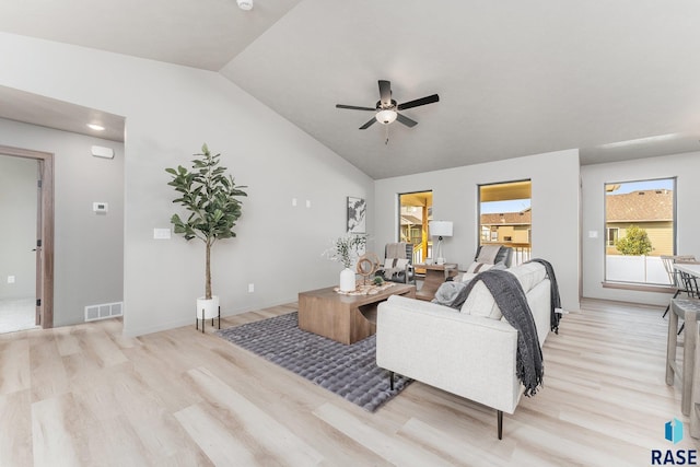 living room with ceiling fan, light hardwood / wood-style floors, and vaulted ceiling