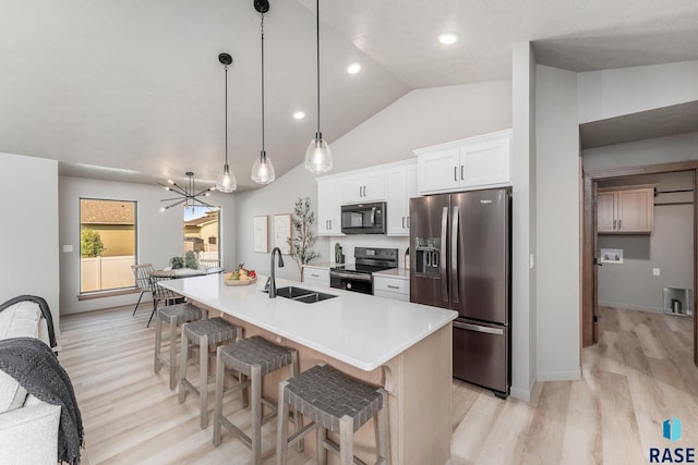 kitchen featuring stainless steel appliances, sink, decorative light fixtures, white cabinets, and an island with sink