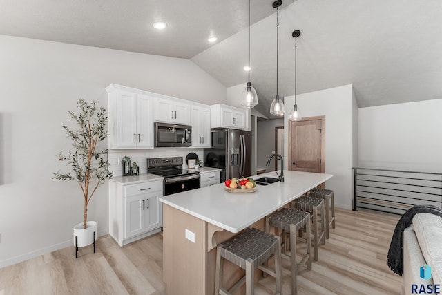 kitchen with pendant lighting, decorative backsplash, an island with sink, appliances with stainless steel finishes, and white cabinetry