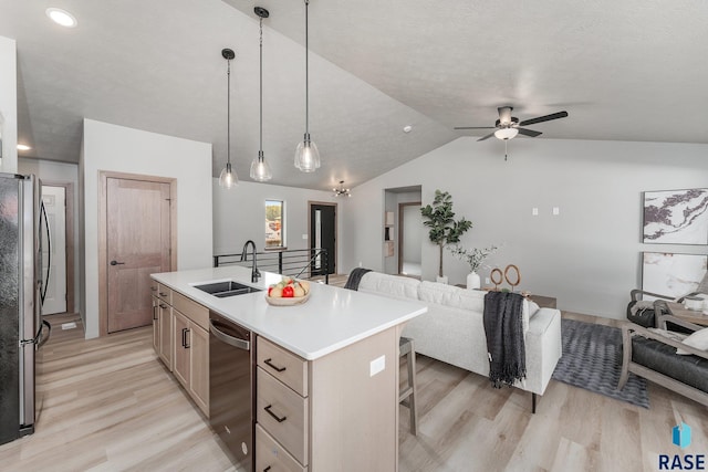 kitchen featuring sink, hanging light fixtures, a kitchen breakfast bar, a kitchen island with sink, and appliances with stainless steel finishes