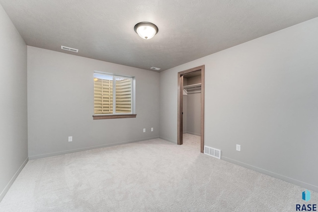 unfurnished bedroom with a closet, light colored carpet, and a textured ceiling